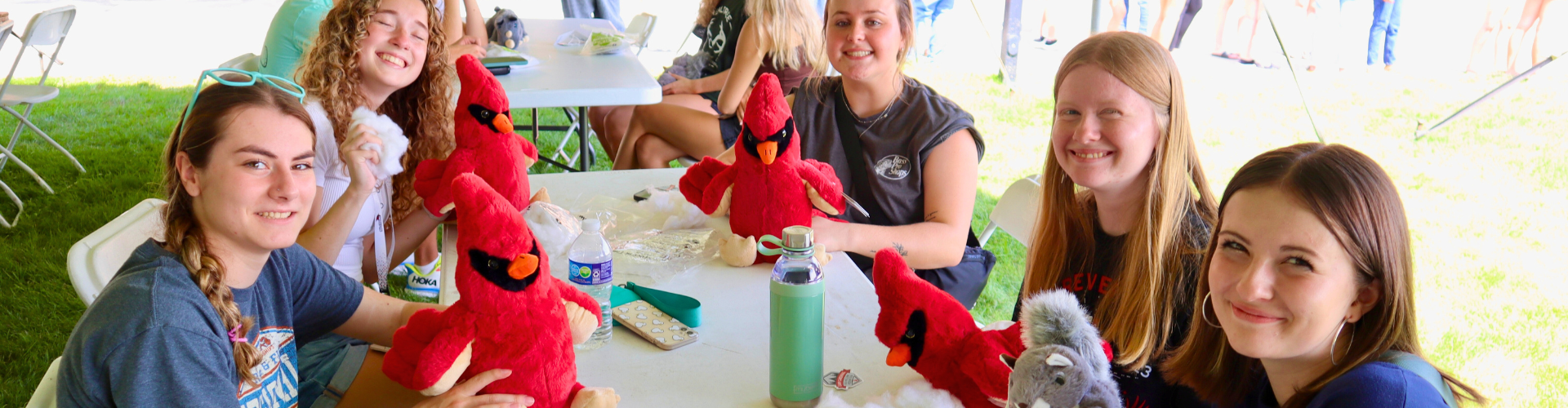 Students seated at a table while stuffing their red Cardinal plushies at the Welcome Weekend Stuff-A-Plush event.